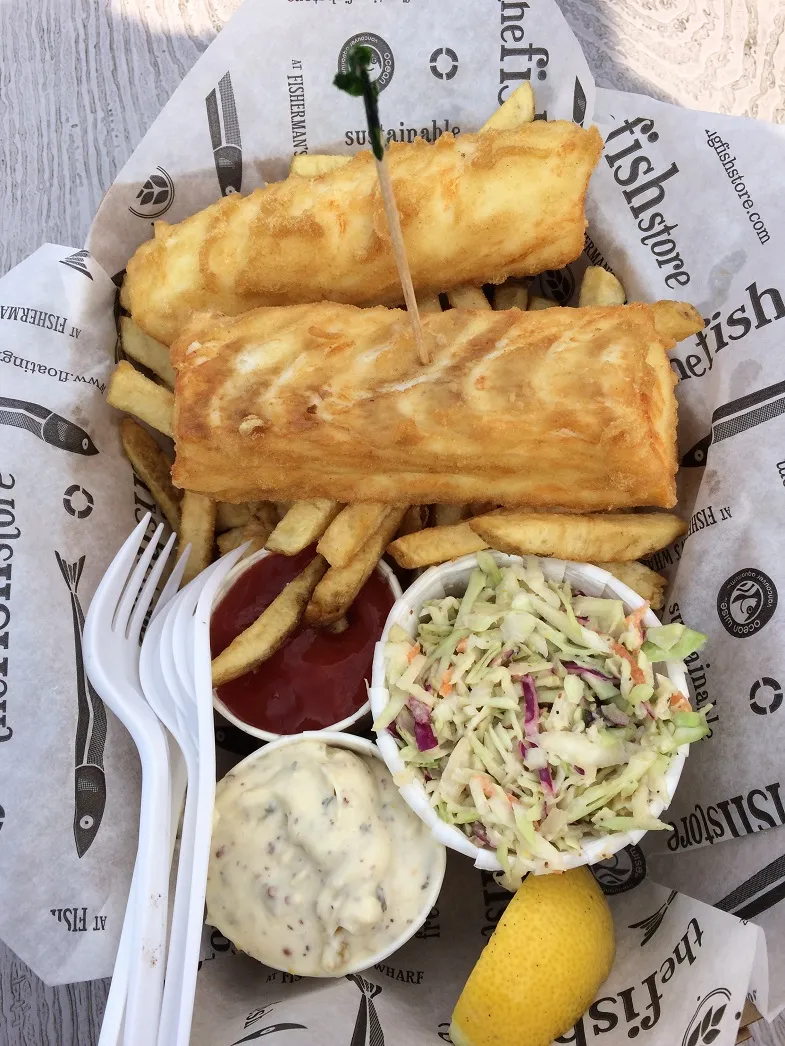Image of the Fish Store’s gluten free fish and chips basket with two pieces of fish, tartar sauce, coleslaw, a piece of lemon and fries.